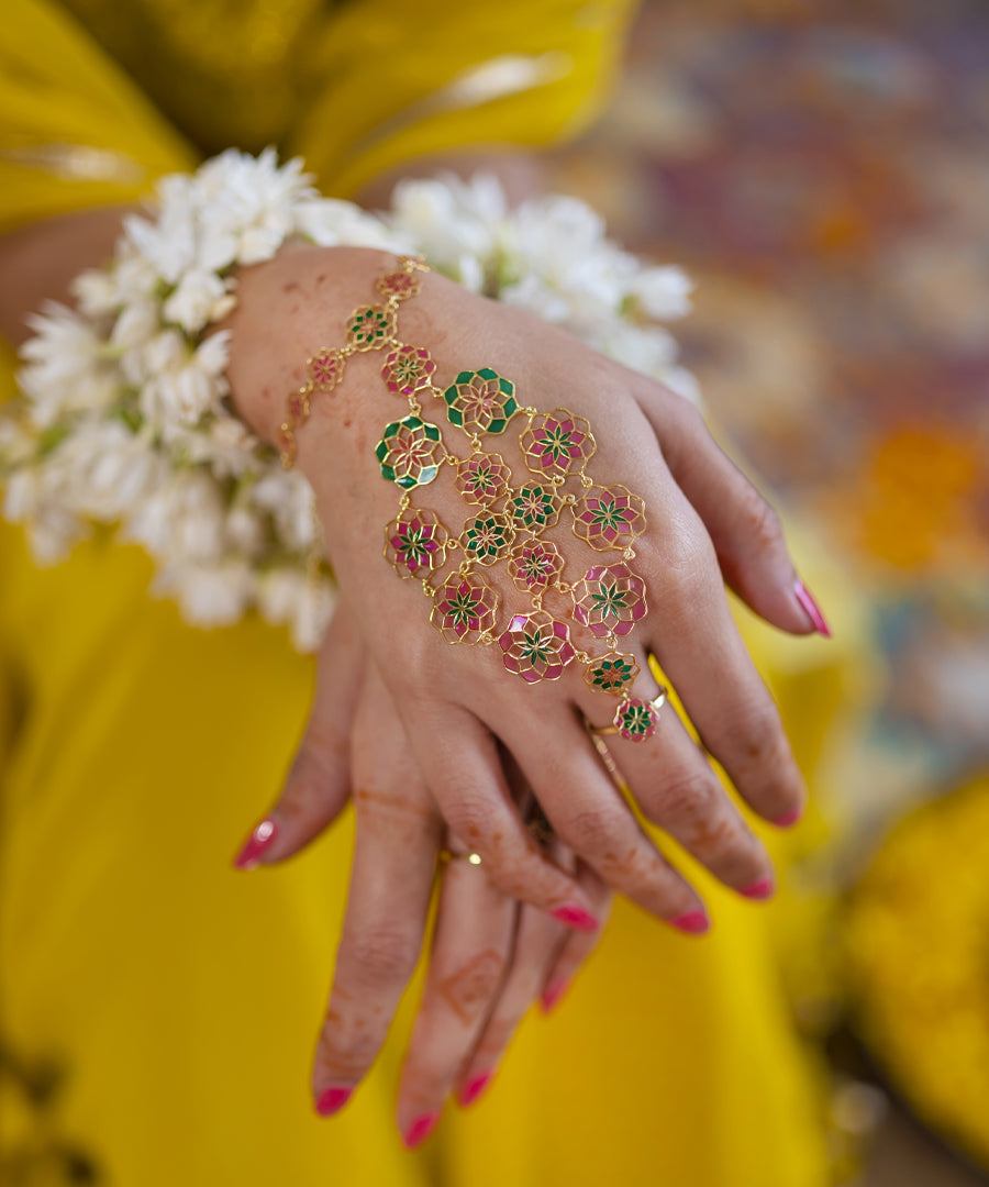 Pink and green hathphool chain bracelet with flower motif design and plated with gold.