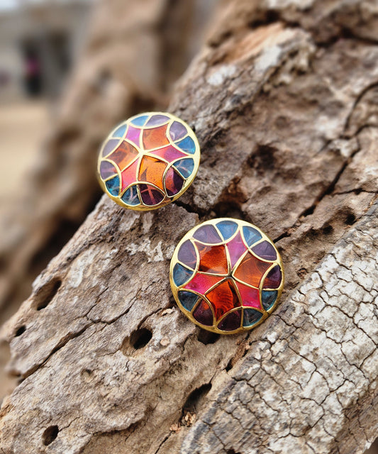 A pair of pink stud earrings lying on wooden block. Silver gold plated earrings from kaleidoscope collection by Manner India.